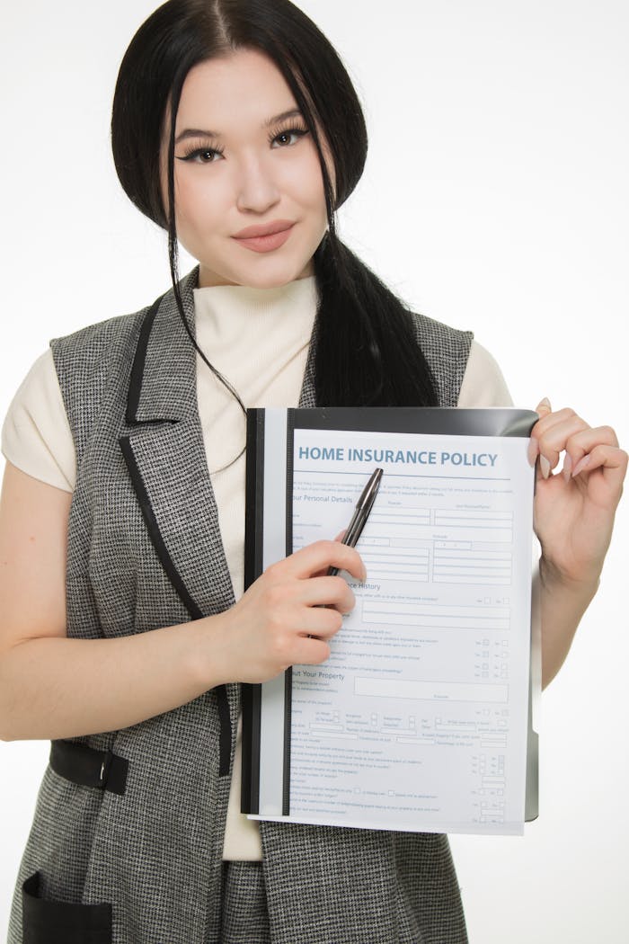 Home Young woman presenting a home insurance policy document while pointing with a pen.